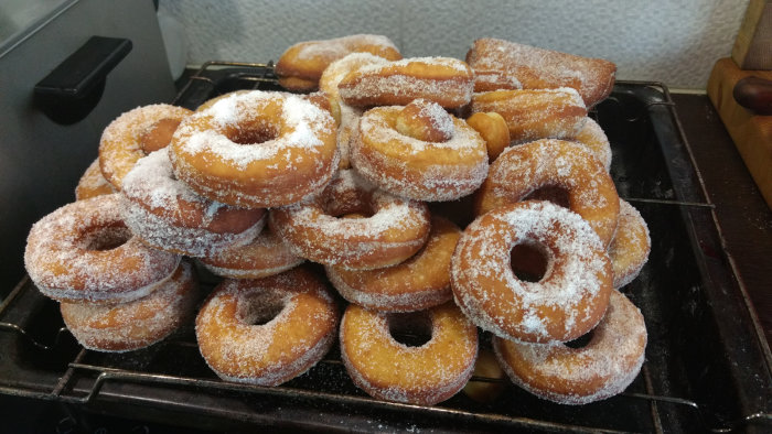 Nystekta munkar med sockerströssel på bakplåt.