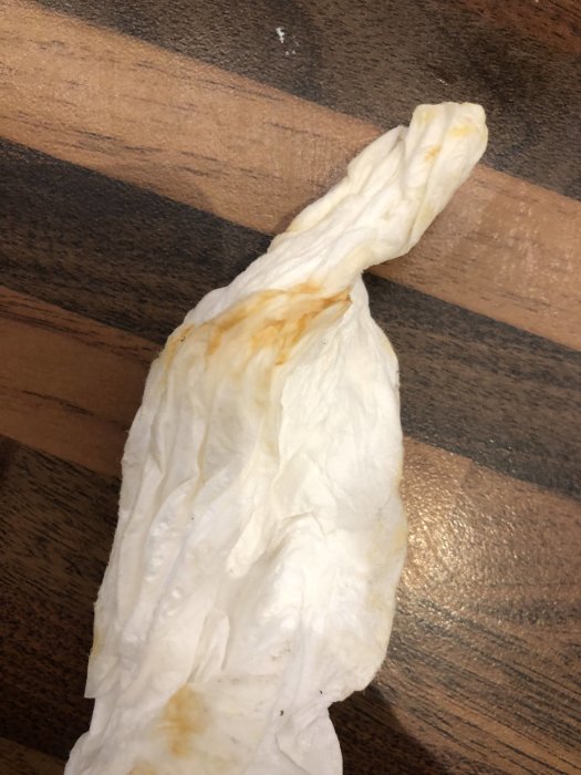 Pappersservett med bruna fläckar mot en träbakgrund som illustrerar föroreningar i vattnet från en egenborrad brunn.