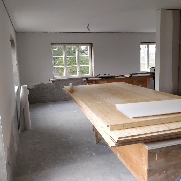 Nyrenoverat rum med nymålade tak och spacklade väggar, arbetsbänk och byggmaterial i förgrunden.