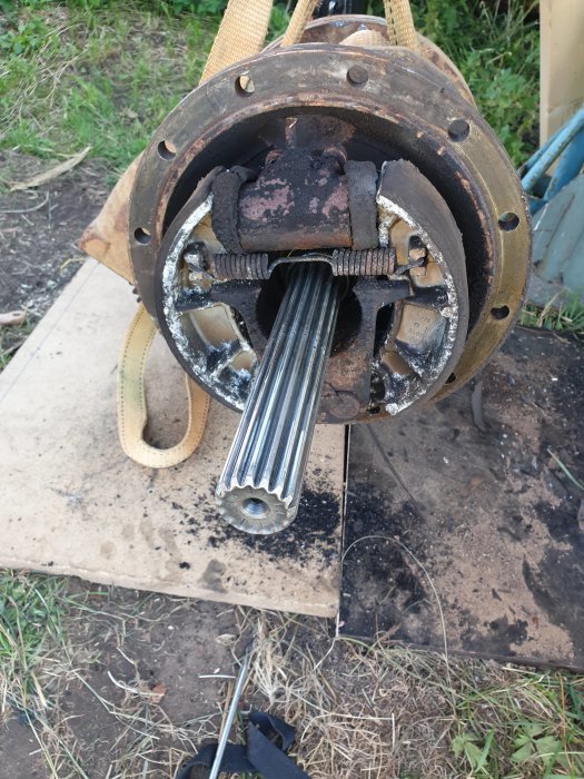 Bild på en demonterad bromscylinder med slipade stolpiller, upphängd och delvis rostig, redo för reparation.