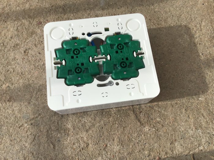 En öppnad Schneider Exxakt 4-vägs eluttag ligger på ett betonggolv, skruvarna är borttagna men enheten är inte helt isär.