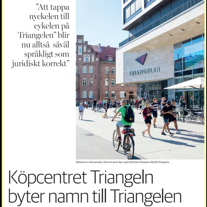 Person på cykel framför köpcentret Triangeln, med människor och byggnader i dagsljus.