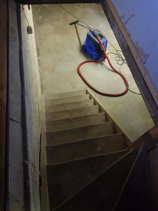 Renoverad trappa med städutrustning och luftrenare i ett gammalt hus.