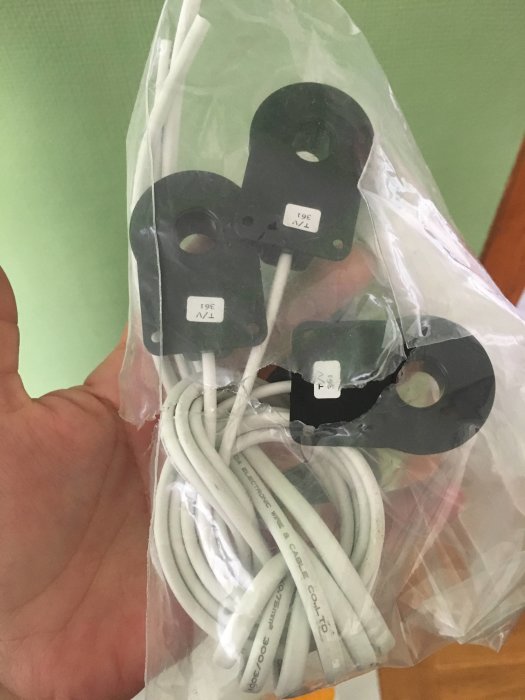 En hand håller en genomskinlig plastpåse med oanslutna elkablar och fastsättningsklämmor.