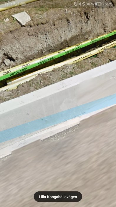 Gasledning, optokabel och kraftledning markerade i grävd schakt.