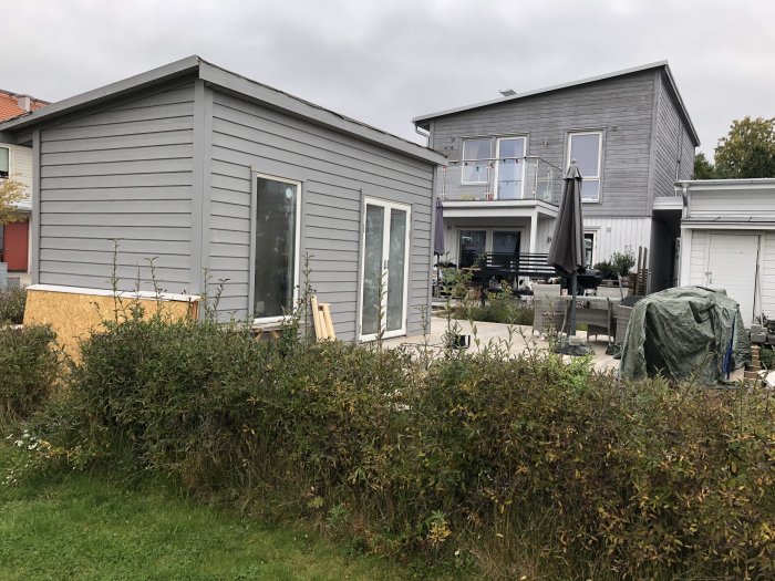 Översiktsbild av ett grått hus under renovering med exponerat tak och byggmaterial runtomkring.