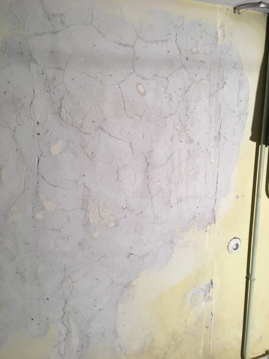 Vägg där färg slipats bort och resulterat i en ojämn yta som behöver spacklas.