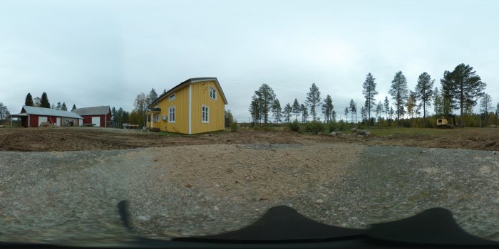 360° bild av byggarbetsplats med gul husfasad, pågående markarbeten och en grävmaskin i bakgrunden.