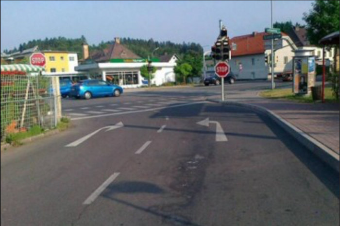 Förvirrande vägmarkeringar vid en korsning med olika pilriktningar och ett stopptecken.