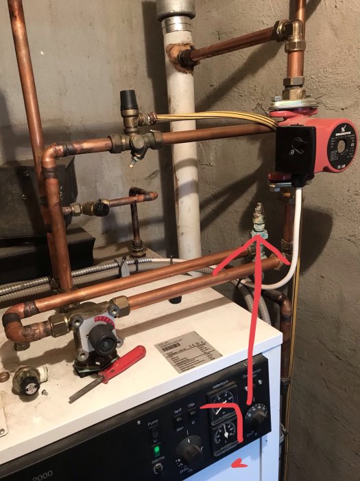 Ärgad ventil på returledning ovanför en kombipanna i ett pannrum, med synliga rör och reglage.