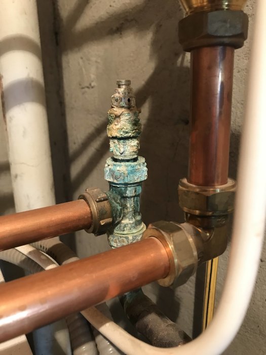 Ärgad ventil eller koppling på returledning med synlig oxidbildning och anslutna kopparrör.