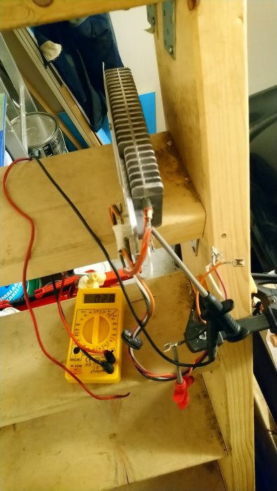 Multimeter mäter motstånd på en kopplingsplint med testkablar fästa, placerad på ett träbord.