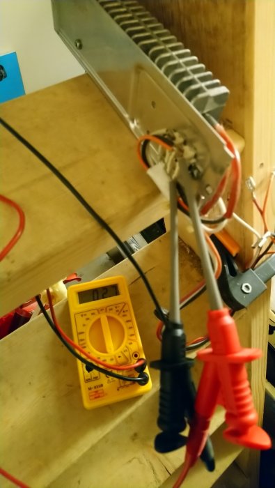 Multimeter mäter motstånd på en kopplingsplint med kablar vid sidan om en värmeelement.