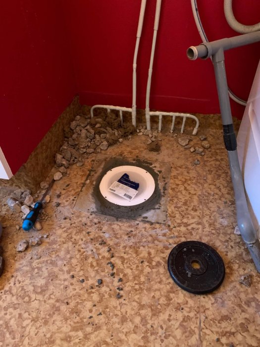 Nyinstallerad golvbrunn i tvättstuga med betongunderlag och synliga rörgenomföringar.