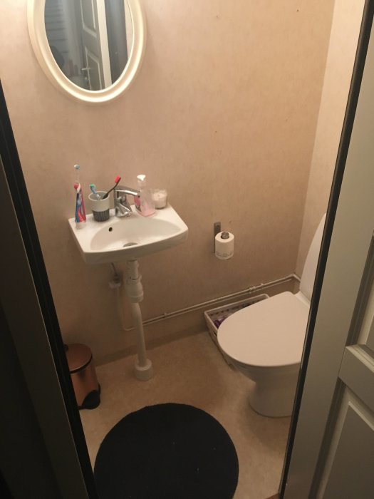 Renoveringsprojekt av badrum med tvättställ, spegel och toalett, inredd med våtrumsmatta.