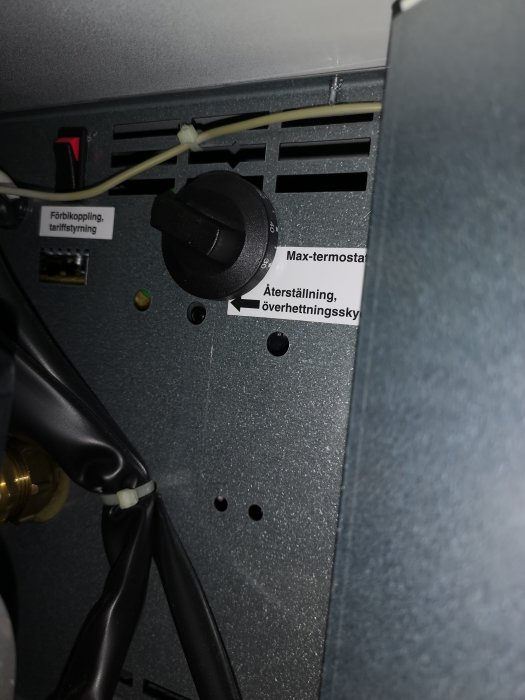 Interiör av en värmepump med termostaten inställd på max och återställningsknapp.