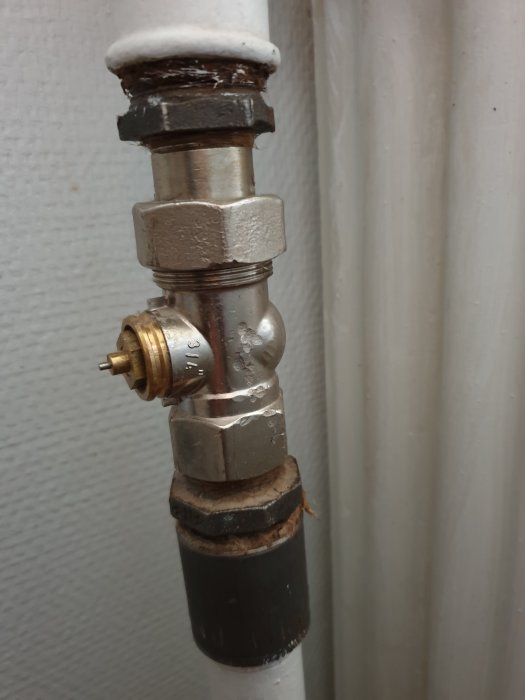 Gammal radiatorventil med lös spak och synliga slitage på anslutningsrör.