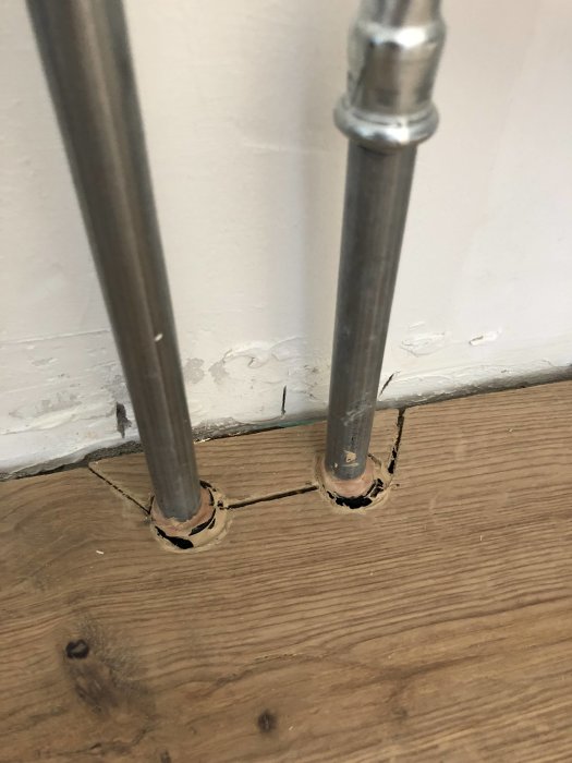 Otillfredsställande golvinstallation med synligt gap på ca 2 cm mellan vägg och trägolv vid rörinstallation.