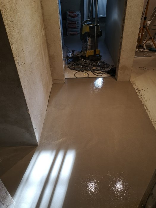 Nyspacklat golv i tvättstuga med Ardex K2000, verktyg och spackelsäckar syns i bakgrunden.