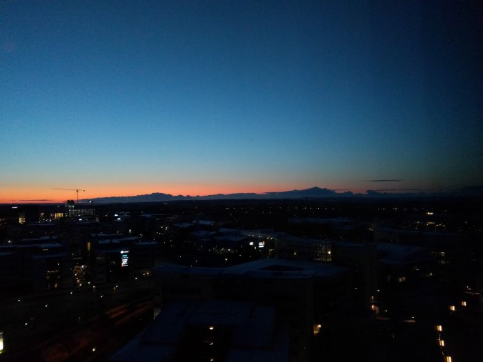 Soluppgångsbild tagen från hotell, vy över stadslandskap med silhuetter av byggnader och berg i fjärran.