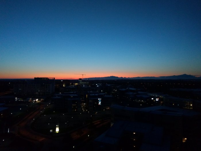 Utsikt från hotellrum 12 våningar upp vid gryning med stadssilhuett och färgrik himmel.