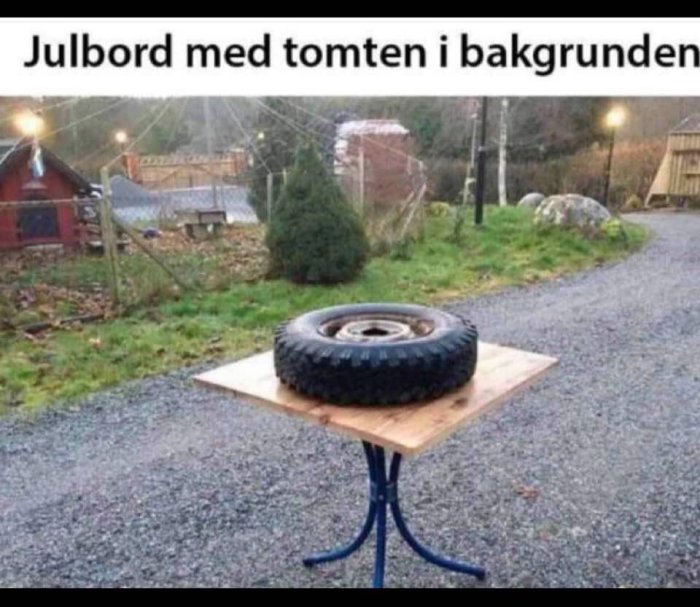 Ett bildäck på ett bord över en blå stol, med en gran och ett rött hus i bakgrunden.