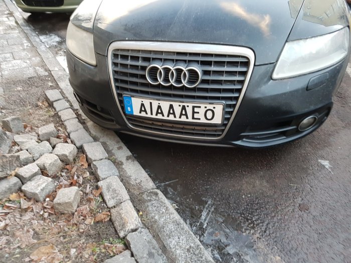 Audi parkerad med framhjulet på en trottoarkant över en vattenpöl.