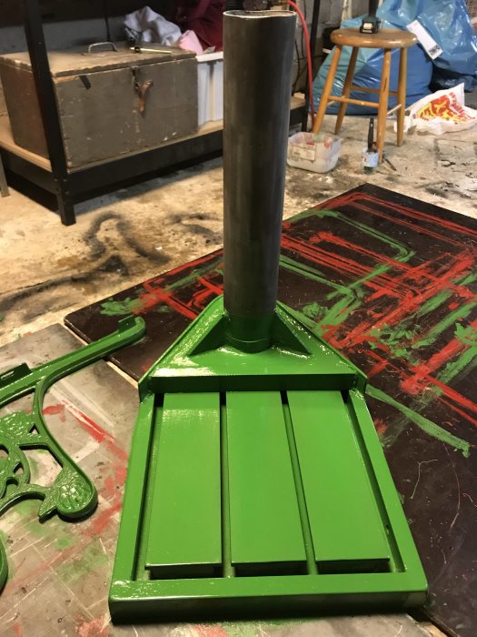 Målad metallkonstruktion i smaragdgrönt, RAL 6001, i ett verkstadsutrymme med sprejmålade golv.
