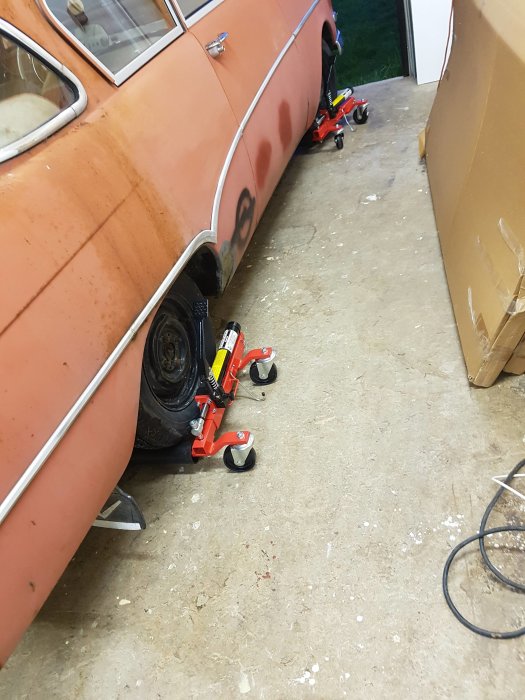 En orange Opel på hjuldollys i ett trångt garage, redo för svängning.