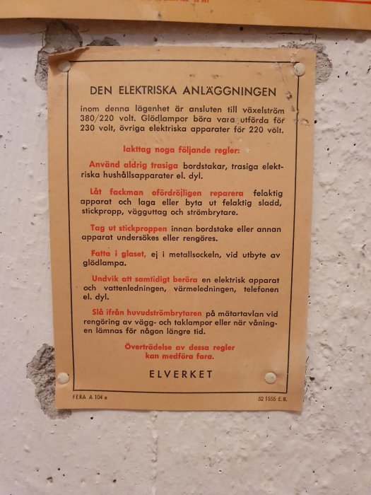 Gammal instruktionstavla för elektrisk anläggning med riktlinjer om säker användning och underhåll på en vit vägg.