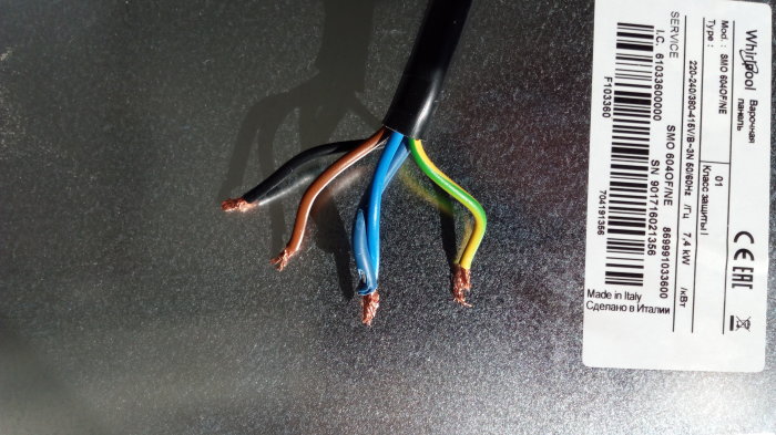 En elektrisk kabel med fem avskalade ledare i olika färger mot grå bakgrund.