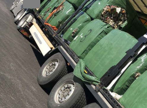 Lastbil som transporterar inplastade balar av sopor.