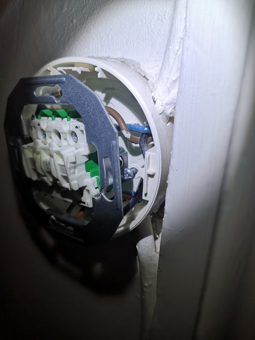 Öppen strömbrytardosa med brun och blå ledning ansluten, redo för dimmerinstallation.