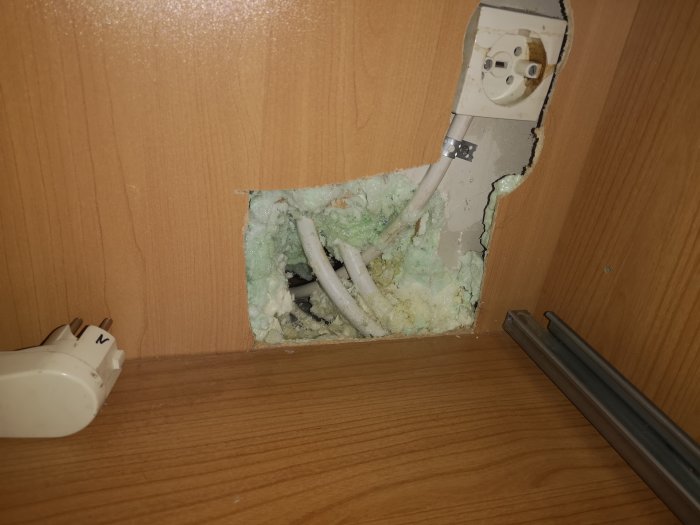 Öppet hål i vägg visar kabeln som försvinner ned i bjälklaget, med isolering och utan synlig skarv.