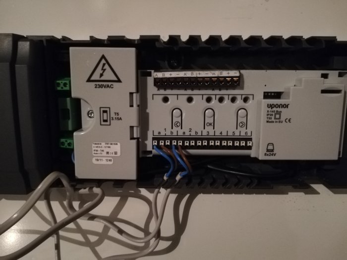Uponor golvvärmesystem med reglercentral Smatrix Base och 24V styrdon mot grå bakgrund.
