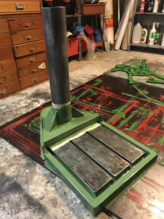Nymlad grågrön metallmaskindel på en verkstadsbänk, omgiven av flaskor och verktyg.