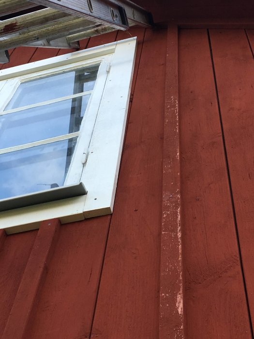 Fönster ovanför röd panelvägg med snedställd locklist och foder ej i våg, vilket visar problem med passning.