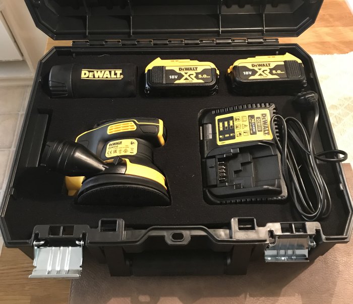 DeWalt DCW210P2 slipmaskin med två 18V batterier och laddare i en öppen svart förvaringslåda.