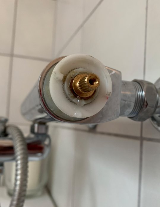 Demonterat tempvred på en badrumsblandare som visar vattenläckage från insatsen.