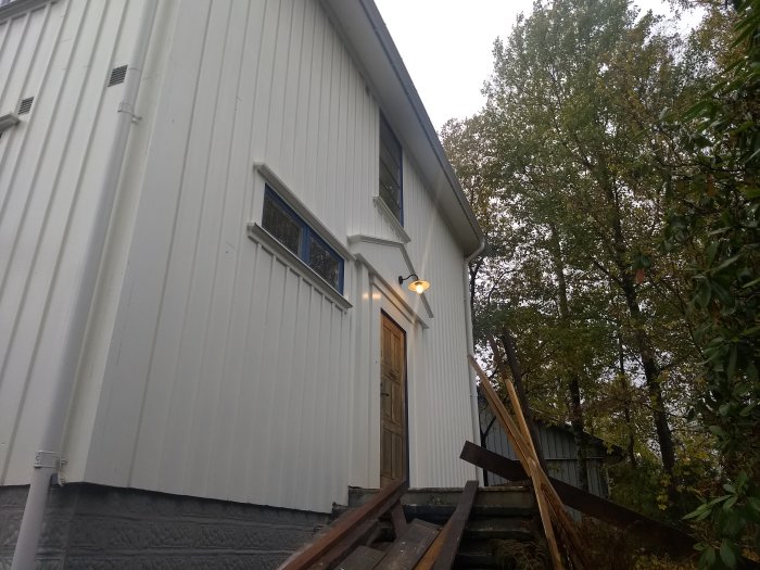 Exteriör av hus med nyinstallerad ytterbelysning tänd vid skymning.