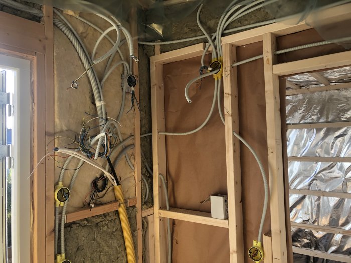 Installation av elledningar och elkablar i en oisolerad vägg med trästomme under en renovering.
