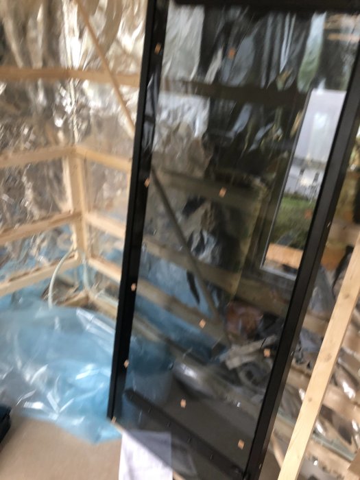 Oskarp bild på en byggplats med en nyinstallerad bastudörr av modellen Harvia Legend i en träkonstruktion.