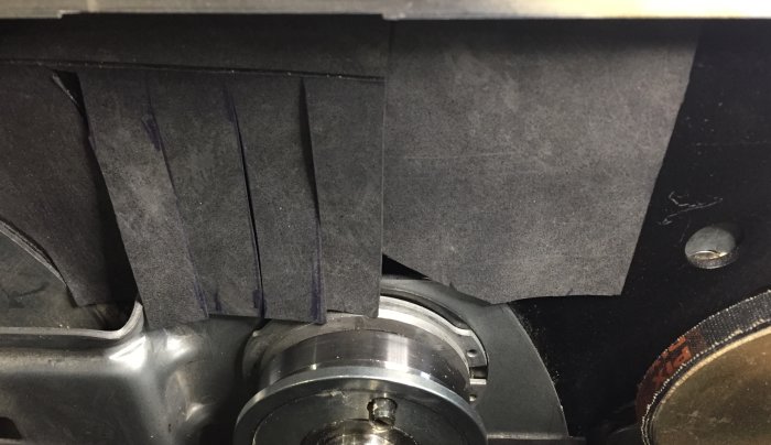 Delvis täckta komponenter i en formatsåg med gummibitar och kardborreband för att minska spånansamling.