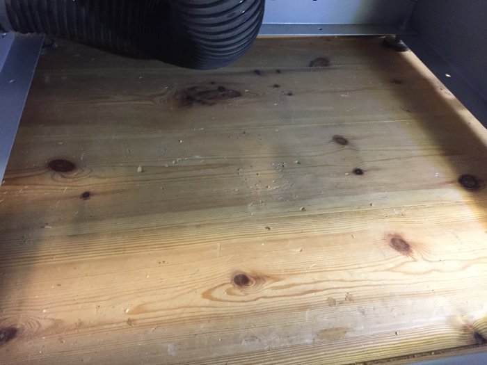 Rengjord botten av formatsåg med spån och anslutningar efter ombyggnad.