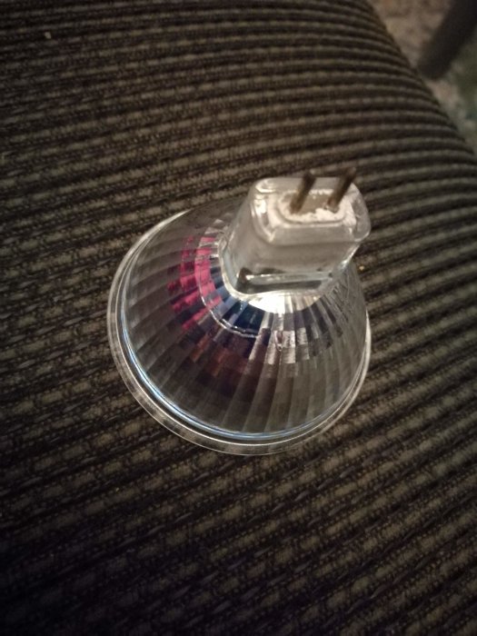 GU 5.3 halogenlampa närbild med två stift på texturerad bakgrund.