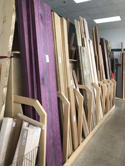 Variety of timber planks in a store, with various sizes and one prominently purple.