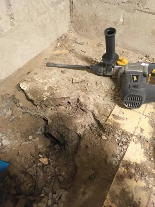 Renovering av källare med borttagen gjutjärnsbrunn och synlig järnmuff i golvet, omgiven av bilade betongytor.