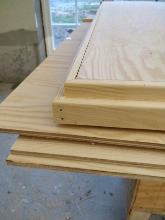 Närbild av hoppskruvad träram och plywoodskivor inför tillverkning av dörrblad.