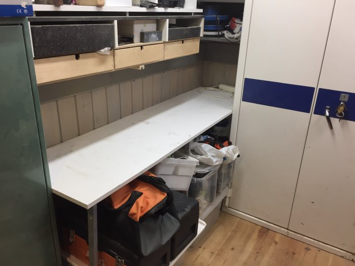 Tomt arbetsbord i sliphörna med verktyg och förvaringslådor under, före omorganisering.