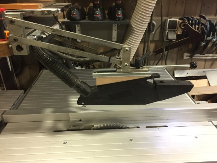 Modiferat sågskydd monterat på en bordsåg, med mekanism från en annan modell och ursprungligt skydd intakt.